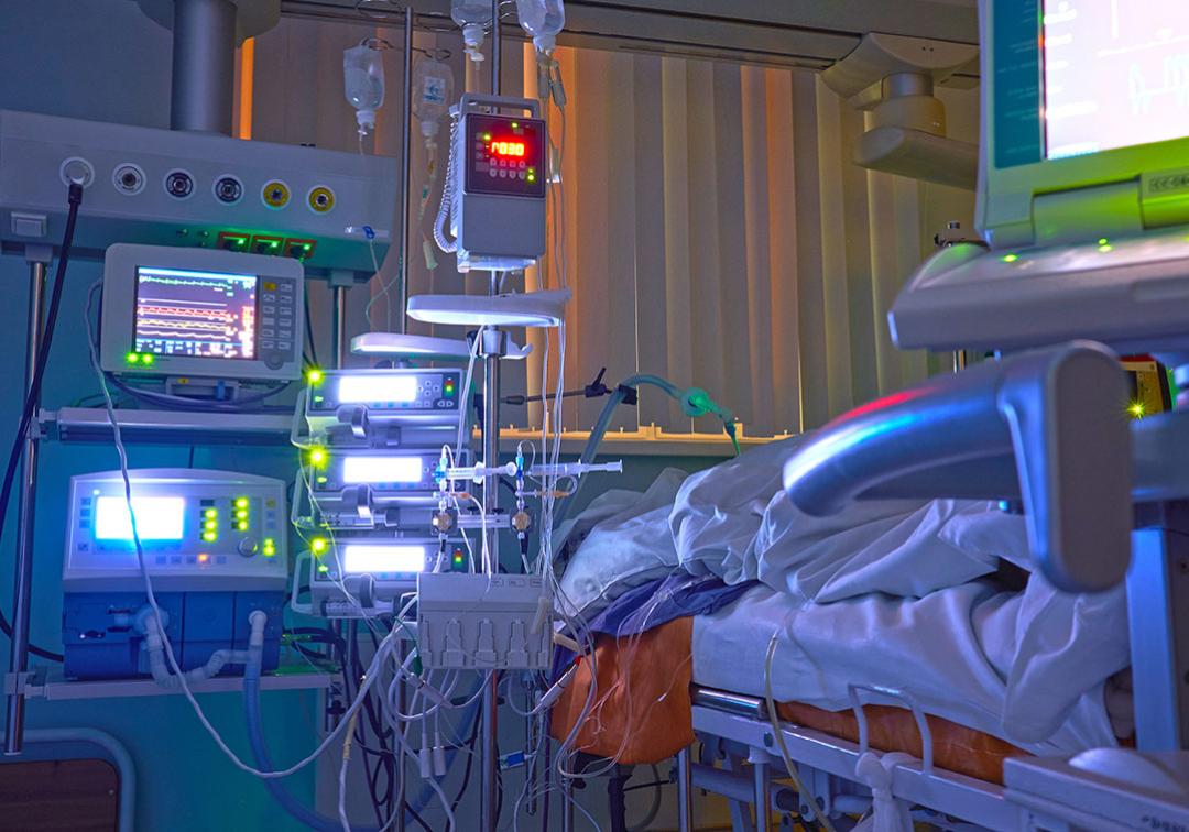A hospital bed surrounded by medical equipment and wires 