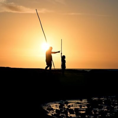 Silhouette of two people spear fishing 