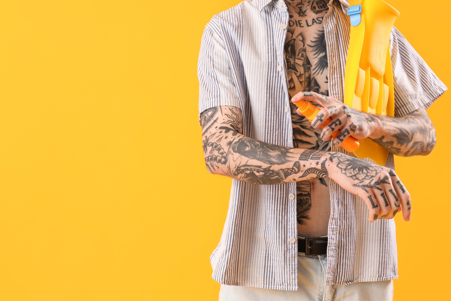 A tattooed man applying sunscreen