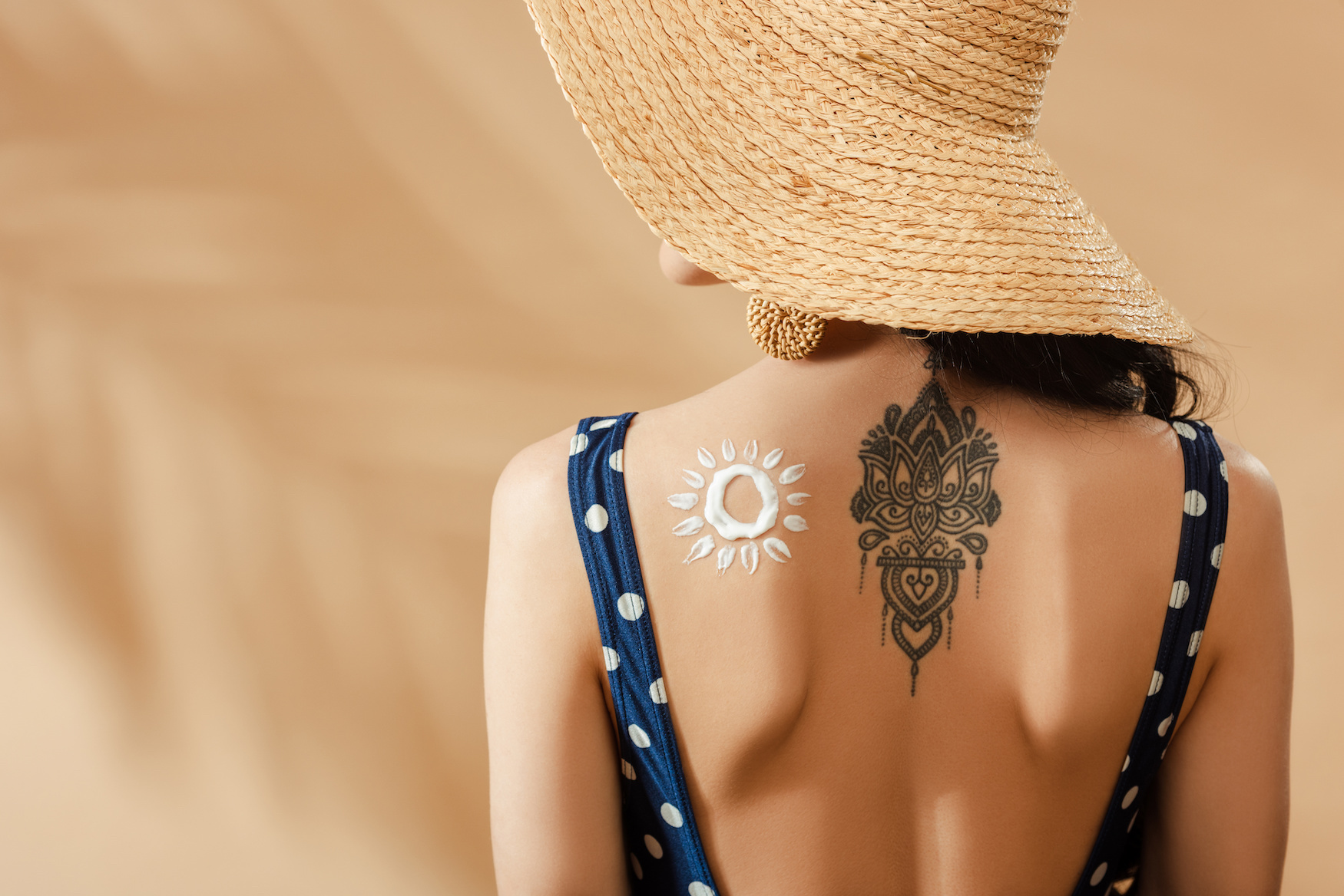 A woman with a tattoo and sunscreen on her back