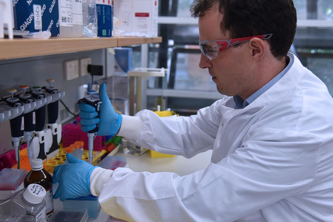 A man in a lab coat using a pippette to conduct an experiment 