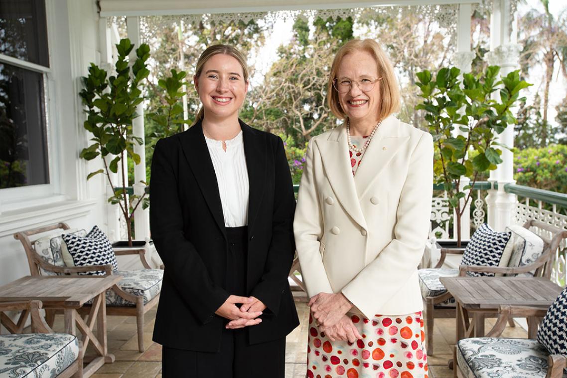 Two women in suits standing on a balcony 