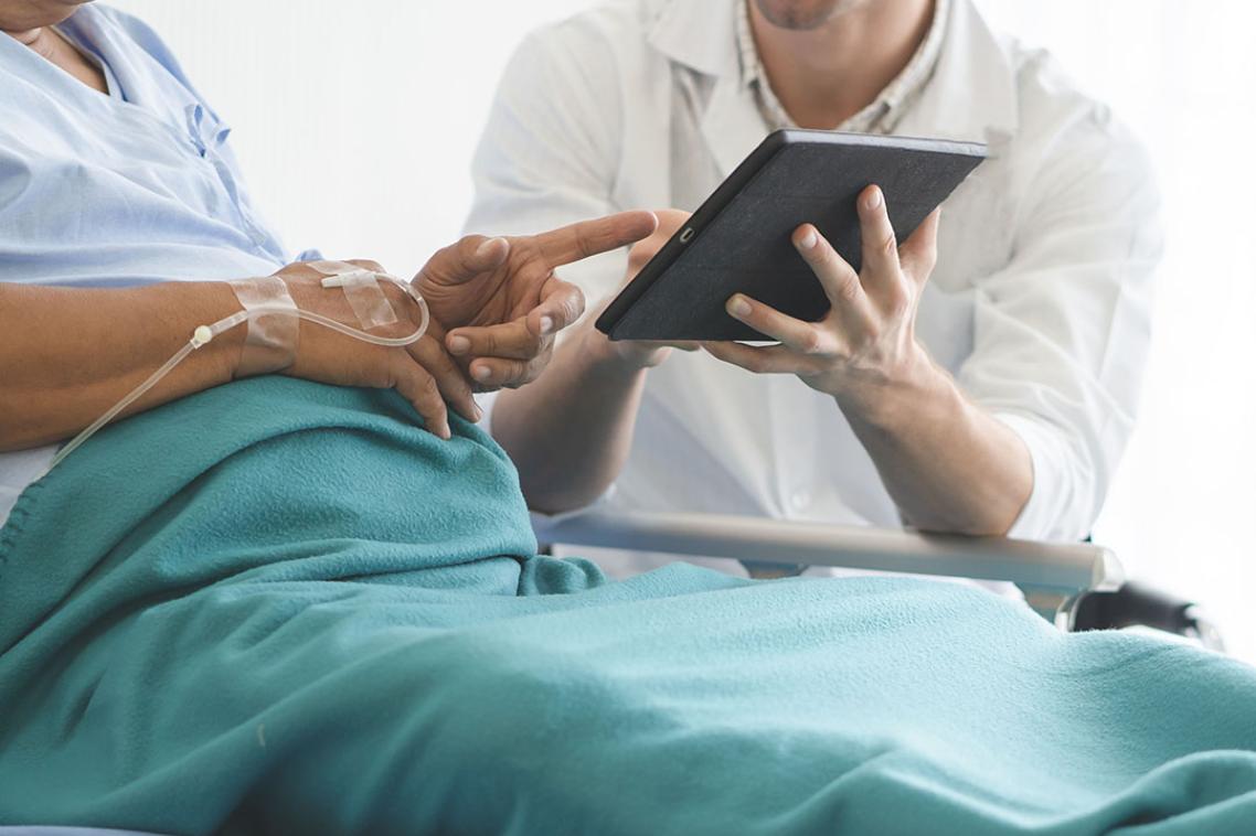 A doctor talking to a patient while showing them an ipad