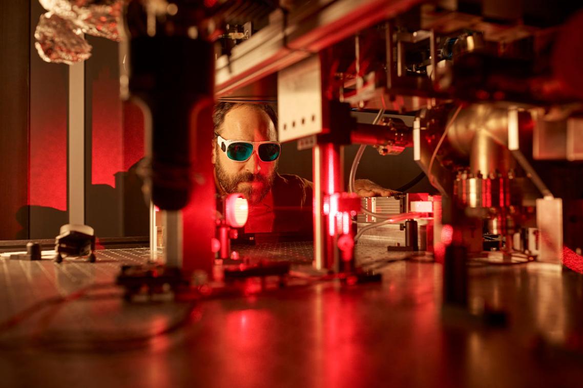 A man in a lab lit up by red LED lights